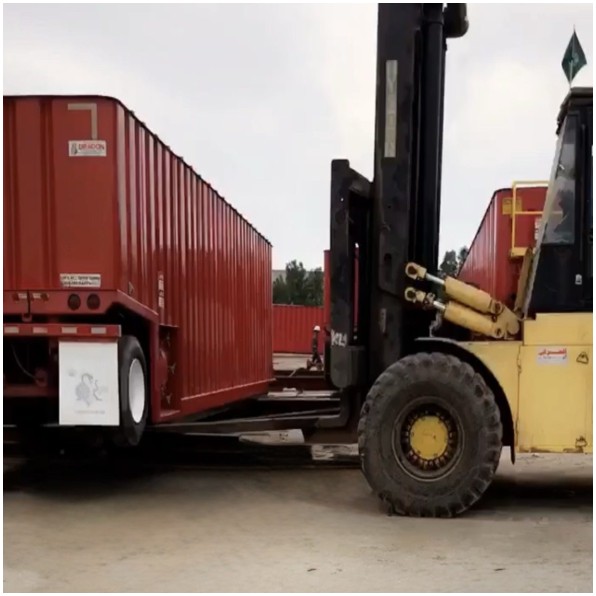 Heavy forklift loading a frac tank onto a trailer